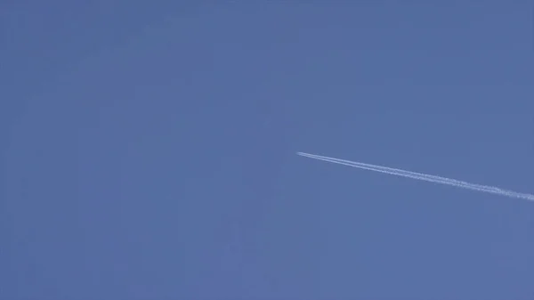 A plane is flying in the sky. Airplane aviation airport contrail the clouds. White airliner transports passengers while it pulling white contrails in dark blue cloudy sky. Airplanes in blue sky with — Stock Photo, Image