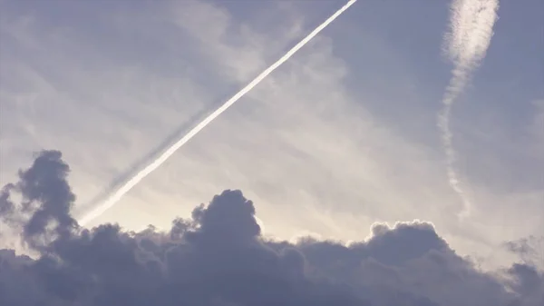 Grande aereo supersonico passeggero che vola alto nel cielo blu chiaro, lasciando lunghe tracce bianche. Aerei che lasciano tracce diagonali su un cielo azzurro chiaro. Una lunga scia di aerei a reazione sul cielo blu — Foto Stock