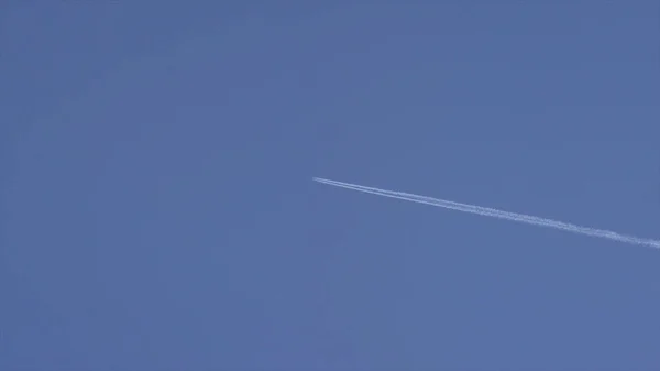 一架飞机在天空飞翔。飞机航空机场轨迹云。白色的客机运送乘客同时它拉在暗蓝色的多云的天空的白色轨迹。飞机在蓝色的天空 — 图库照片