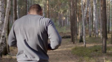 Ormanda görünümü aracılığıyla bir doğa iz boyunca arkadan çalışan erkek atlet. bir yaz orman yoluyla vücut parçası geri çalışan erkek atlet. Sonbahar orman içinden çalışan yalınayak erkek