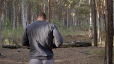 Ormanda görünümü aracılığıyla bir doğa iz boyunca arkadan çalışan erkek atlet. bir yaz orman yoluyla vücut parçası geri çalışan erkek atlet. Sonbahar orman içinden çalışan yalınayak erkek