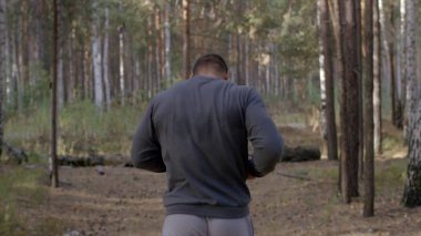 Ormanda görünümü aracılığıyla bir doğa iz boyunca arkadan çalışan erkek atlet. bir yaz orman yoluyla vücut parçası geri çalışan erkek atlet. Sonbahar orman içinden çalışan yalınayak erkek