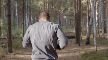 Ormanda görünümü aracılığıyla bir doğa iz boyunca arkadan çalışan erkek atlet. bir yaz orman yoluyla vücut parçası geri çalışan erkek atlet. Sonbahar orman içinden çalışan yalınayak erkek