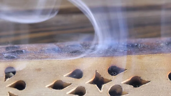 Belo aroma fumaça perto da estatueta. uddha Figura no Chaban de madeira da placa do chá com uma fumaça do aroma. Macro Close Up de queima de paus de incenso com fumaça sobre fundo marrom . — Fotografia de Stock