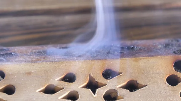 Belo aroma fumaça perto da estatueta. uddha Figura no Chaban de madeira da placa do chá com uma fumaça do aroma. Macro Close Up de queima de paus de incenso com fumaça sobre fundo marrom . — Fotografia de Stock