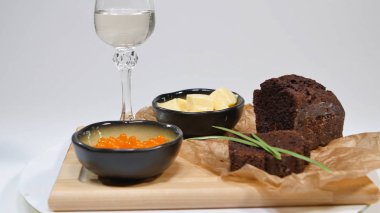 Fesleğen ve Studio ekmek üzerine tereyağı ile taze kırmızı havyar. Şarap gözlük arka plan üzerinde kırmızı havyar ile yetiştirilmiş. Buz ve küçük aperatifler tereyağı ve kırmızı havyar ile soğuk Rus votka