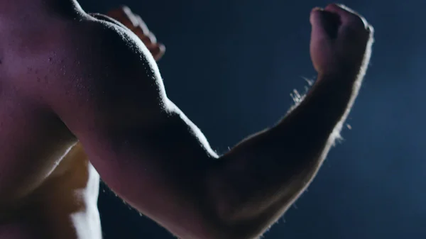 Fighter silhouette. Handsome athletic man in boxing stand on a dark background. Muscular young man in boxing gloves and shorts shows the different movements and strikes — Stock Photo, Image