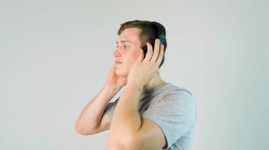 Genç adam onun kulaklık ve beyaz arka planda müzik dinlemek koyar