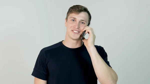 Šťastný úsměv mladý muž mluví na mobilní izolované na bílém pozadí — Stock fotografie