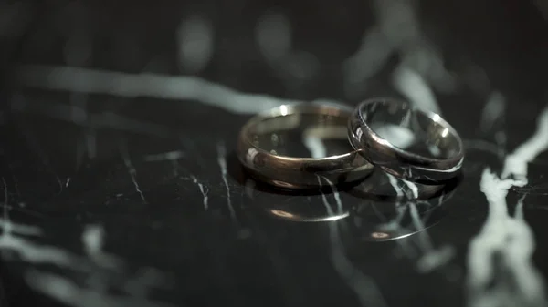Anéis de casamento em uma mesa de pedra de mármore preto. Dois anéis em uma mesa de mármore preto — Fotografia de Stock