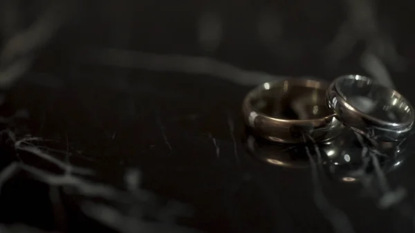 Anéis de casamento em uma mesa de pedra de mármore preto. Dois anéis em uma mesa de mármore preto — Fotografia de Stock