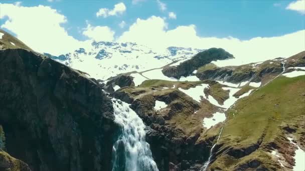 Живописный вид на реку с белой водой и далекую гору с высоким водопадом. Вид с вершины водопада и заснеженных гор — стоковое видео