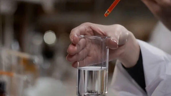 Un joven científico trabaja en un laboratorio biológico moderno. Un investigador con una bata de laboratorio estudiando una pieza de equipo para un experimento. La microelectrónica. La ciencia, concepto de laboratorio científico —  Fotos de Stock