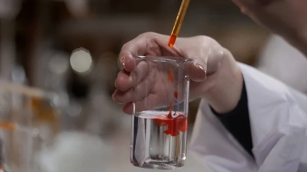 Un joven científico trabaja en un laboratorio biológico moderno. Un investigador con una bata de laboratorio estudiando una pieza de equipo para un experimento. La microelectrónica. La ciencia, concepto de laboratorio científico — Foto de Stock