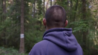 Arkadan Görünüm ile kulaklık daimi ve ormandaki müzik dinlerken insanın. Üst düzey runner ile kulaklık germe yapıyor. Sonbahar doğa.