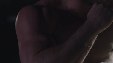 Savaşçı siluet. Yakışıklı atletik adam boks standında karanlık bir arka plan üzerinde. Kas genç adam boks eldivenleri ve şort farklı hareketleri ve grevler gösterir