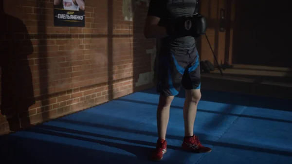 Sombra de luchador con guantes de boxeo cerca de la pared de ladrillo. El joven está parado al lado de la pared por la noche. Gran sombra en la pared. Linterna está brillando . — Foto de Stock