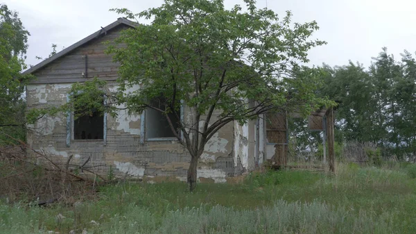 Uma antiga casa abandonada na aldeia, num fundo de árvores. Casa abandonada perto de Donetsk. Casas e ruínas destruídas, mecanismos Ucrânia — Fotografia de Stock