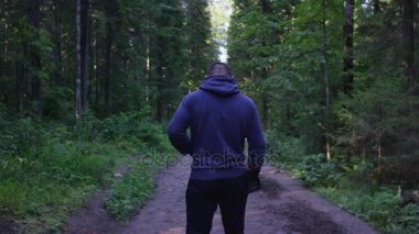 Genç adam ormanda bir şapka. Atlet spor yapmak için ormana geldi