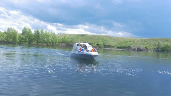 Um barco de recreio com duas pessoas a bordo está a chegar. Elegante barco a motor moderno está na doca no dia de verão do rio baía — Fotografia de Stock