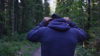 Genç adam ormanda bir şapka. Atlet spor yapmak için ormana geldi