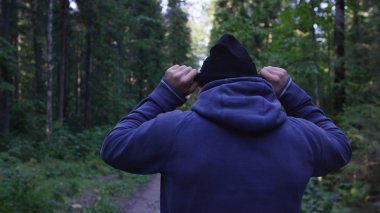 Genç adam ormanda bir şapka. Atlet spor yapmak için ormana geldi