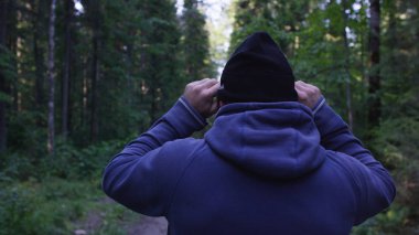 Genç adam ormanda bir şapka. Atlet spor yapmak için ormana geldi