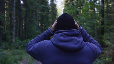 Genç adam ormanda bir şapka. Atlet spor yapmak için ormana geldi