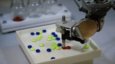 Otomatik robot ilaç endüstrisi. Robot otomatik olarak sıralama topları. Robot hapları rengine göre sıralar.