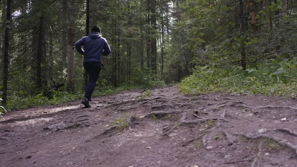 Joven hombre en forma corriendo en el bosque. Joven atleta corriendo en el bosque — Foto de Stock