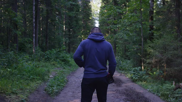 Genç adam ormanda bir şapka. Atlet spor yapmak için ormana geldi