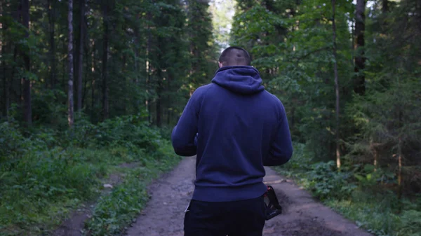 Genç adam ormanda bir şapka. Atlet spor yapmak için ormana geldi