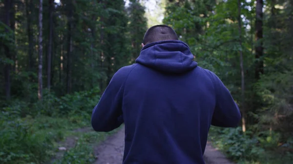 Um jovem a usar um chapéu na floresta. Atleta entrou na floresta para fazer esportes — Fotografia de Stock