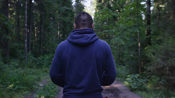 Yüz yüze bir başlık ayakta. Ormanda kapüşonlu adam. Spor niteliğine ormandaki