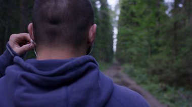 Atletik erkek yolda orman kulaklıklarla. Sonbahar Orman ile iz üzerinde ayakta atletik adam. Arkadan görünüm