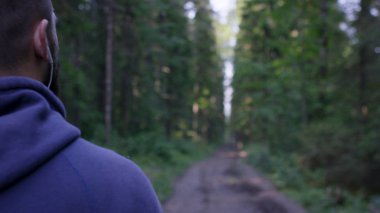 Atletik erkek yolda orman kulaklıklarla. Sonbahar Orman ile iz üzerinde ayakta atletik adam. Arkadan görünüm