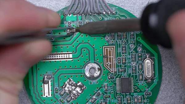 Ruka drží pájka a práci s hlavní opravy deska elektronické na pohled shora. Mužské ruce zblízka pájení mikročip. Páječka — Stock fotografie