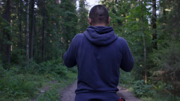 Persona en una capucha de pie. Hombre en el barrio en el bosque. Deporte en el bosque en la naturaleza — Foto de Stock