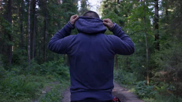 Person mit Kapuze stehend. Mann mit Kapuze im Wald. Sport im Wald in der Natur — Stockfoto