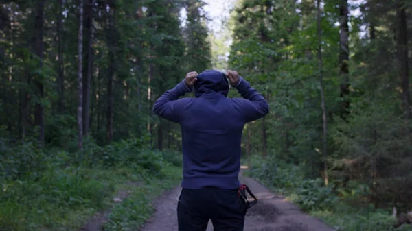 Pessoa em pé de capuz. Um homem no capô na floresta. Desporto na floresta sobre a natureza — Fotografia de Stock