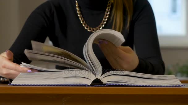 Las manos de las mujeres hojeando un libro. Mujer sentada a la mesa hojeando el libro — Vídeos de Stock