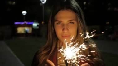 Bir maytap tutan güzel gülümseyen genç kadın. Gece sahne. Maytap elinde tutan genç gülümseyen kız. Tatil kavramı