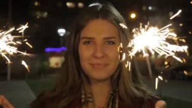 Bir maytap tutan güzel gülümseyen genç kadın. Gece sahne. Maytap elinde tutan genç gülümseyen kız. Tatil kavramı