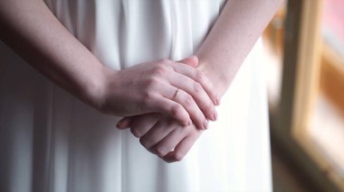 Pencerenin kalan beyaz elbiseli kız. Kızlar el ile nikah yüzüğü ya da nişan yüzüğü. Güzel genç kadın evde pencere yakınındaki beyaz elbise kalmak. Zarif. Sabah gelin.