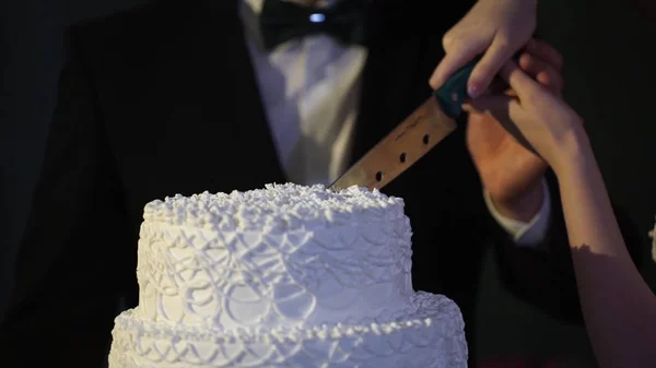 Руки жениха и невесты вырезаны из куска свадебного торта. Жених и невеста на свадебном приёме, режут свадебный торт. Жених и невеста разрезали свадебный торт — стоковое фото