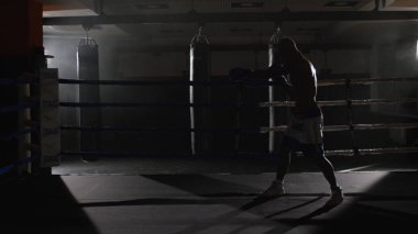 Ringde kickbox savaşçı gölge boks. Atlet gölgesi ile savaşıyor. O ringde çalışır gibi onun yumruklar üzerinde bandaj ile bir yumruk atma eğitim genç boksör