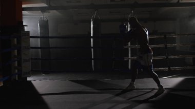Ringde kickbox savaşçı gölge boks. Atlet gölgesi ile savaşıyor. O ringde çalışır gibi onun yumruklar üzerinde bandaj ile bir yumruk atma eğitim genç boksör