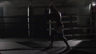 Ringde kickbox savaşçı gölge boks. Atlet gölgesi ile savaşıyor. O ringde çalışır gibi onun yumruklar üzerinde bandaj ile bir yumruk atma eğitim genç boksör