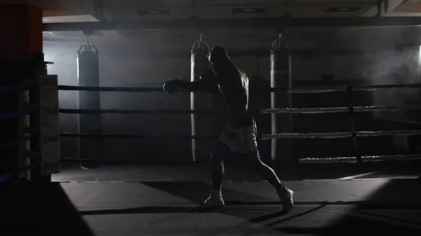 Combattente Shadowboxing sul ring di allenamento. Combattente professionista. Boxer maschile in abbigliamento sportivo di formazione, un esercizio in palestra, lotta con un'ombra sul ring, Test di sciopero — Foto Stock