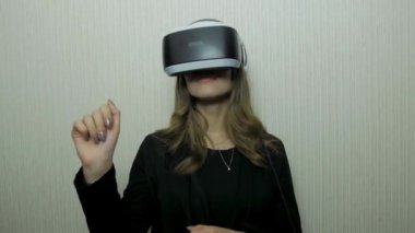 Aamazed genç bir kadın Vr deneyimi sırasında hava dokunmadan. Gelecek şu andır. Onun Vr kulaklık ayarlama ve evde otururken gülümseyen çekici genç kadın